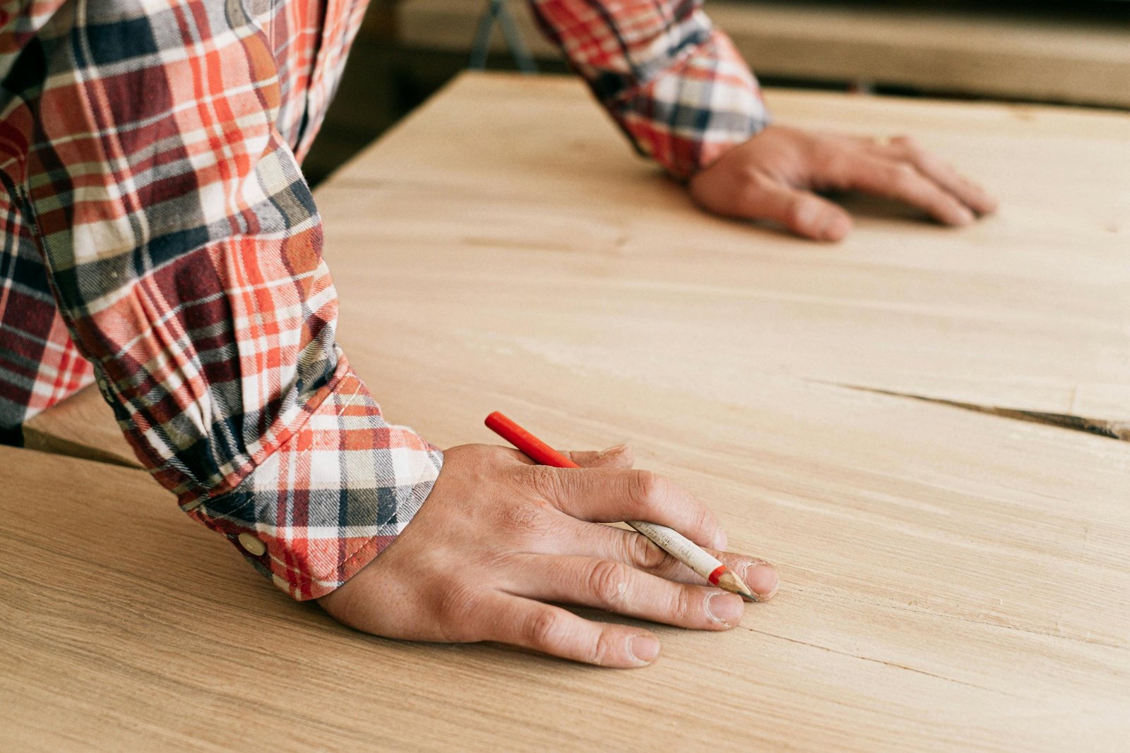 A craftsman marking wood in a workshop, focusing on precision and detail.
